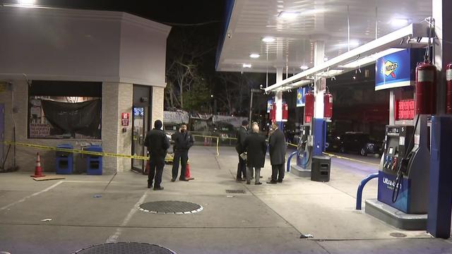 Police stand outside a gas station blocked off by police tape. 