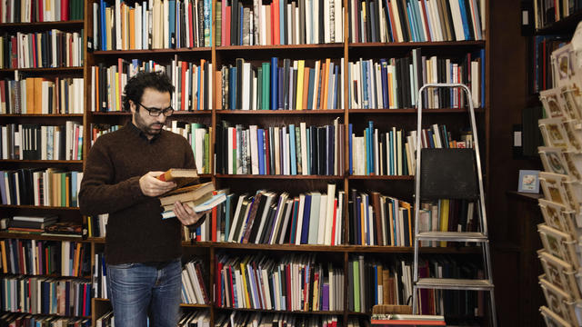 Customer choosing book while standing against bookshelves 