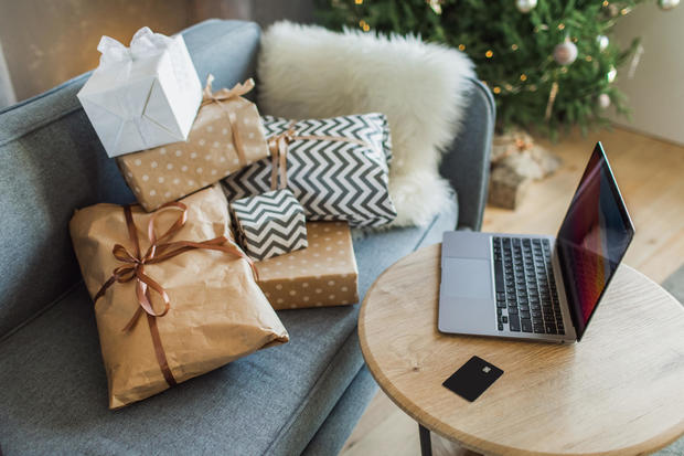 Blue sofa with gifts and table with laptop and credit card for online Christmas shopping. 