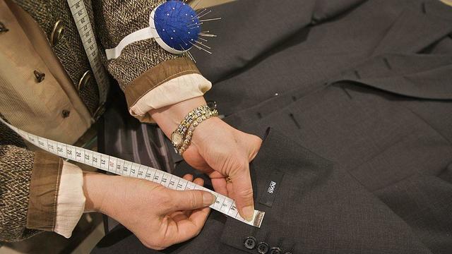 A tailor measures the length of the sleeves on a Hugo Boss s 
