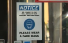 Window sing informing people to wear a protective face mask indoors 