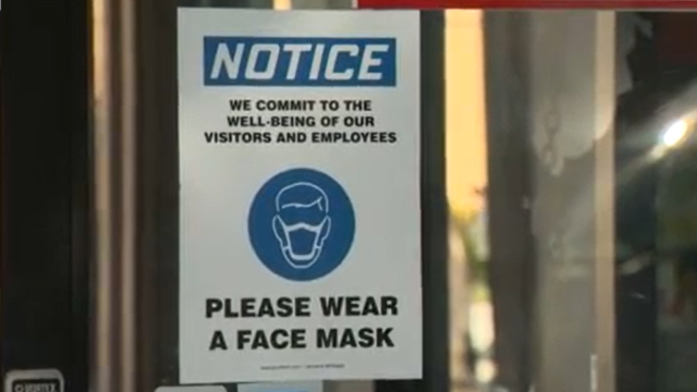 Window sing informing people to wear a protective face mask indoors 