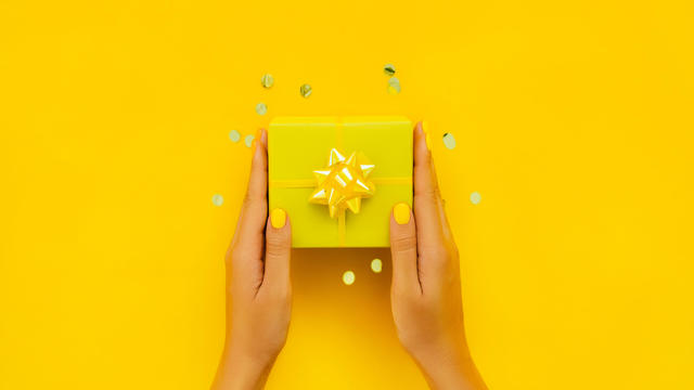 Woman holding yellow gift box. Giving new year or birthday present. 