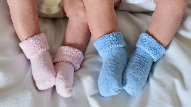 Twins lie in a baby bed and wear pink and blue socks in Frankfurt (Oder), Germany, 14 April 2015. 