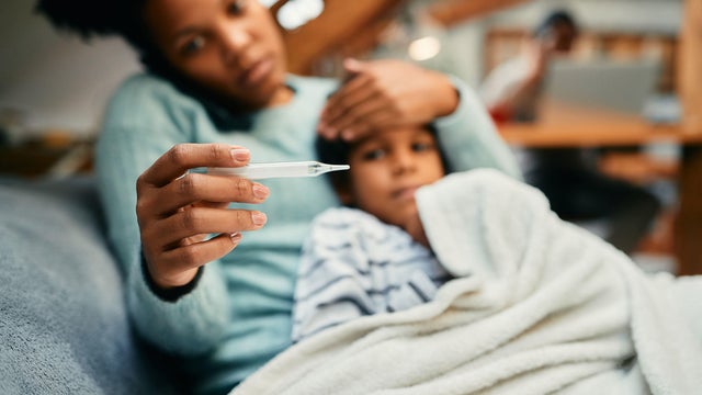 Close-up of black mother measuring sick son's temperature. 