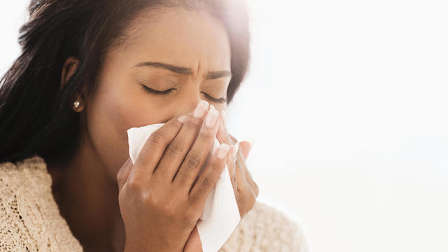 Mixed race woman blowing her nose 