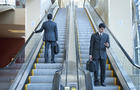 Businessmen standing on escalators 