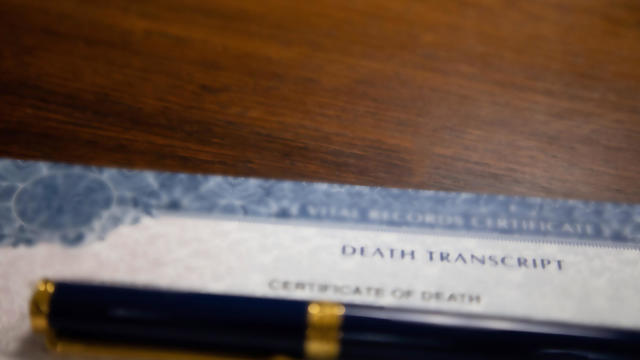 death certificate on wooden desk under pen 