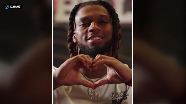 Damar Hamlin smiles at the camera and makes a heart shape with his hands. 