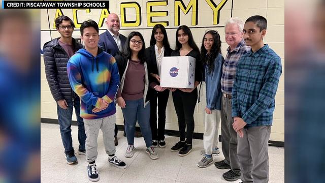 Students and instructors pose with a box with the NASA logo on it. 
