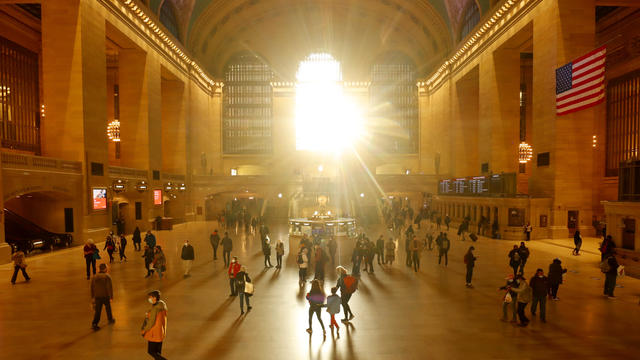 People walk through Grand Central Terminal as the sun rises through its east facade windows on November 6, 2021, in New York City. 