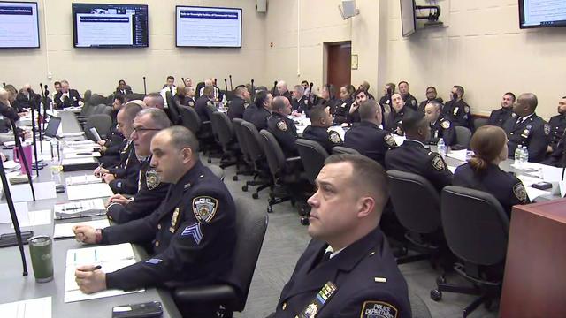 Dozens of NYPD officers sit at long tables. 