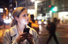 Lady in the city at night with her phone 