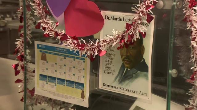 A lunch calendar is posted in the cafeteria kitchen at Nyack Middle School next to a poster of Dr. Martin Luther King Jr. and Valentine's Day decorations. 