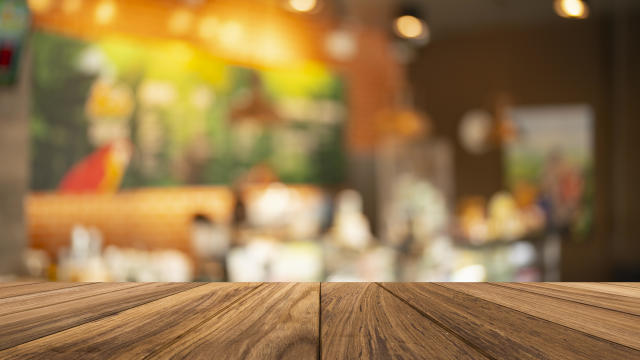 Wood table top on blurred of counter cafe shop with light bulb.Background 
