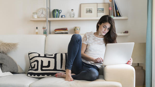 Woman sitting on couch with laptop computer 