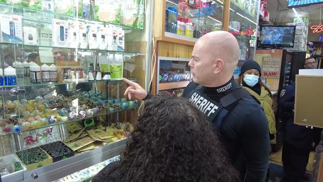 A member of the New York City sheriff's office looks at products inside an illegal smoke shop. 
