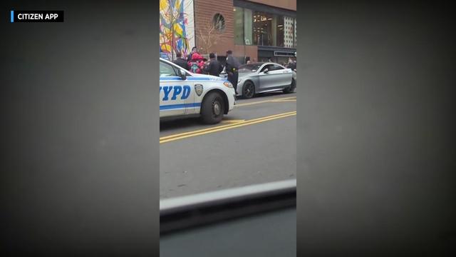 NYPD officers stand near a vehicle. 