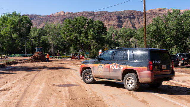 A police car blocks the street so mud can be cleaned up after a flash flood the night before.  Moab, Utah. 
