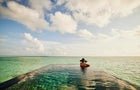 Extreme wide shot of mature woman relaxing in infinity pool 