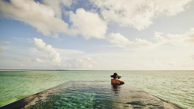 Extreme wide shot of mature woman relaxing in infinity pool 