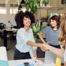 Happy businesswoman shaking hand with colleague at work place 