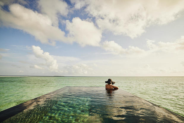 Extreme wide shot of mature woman relaxing in infinity pool 