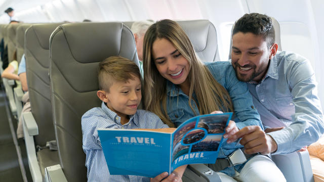 Family traveling by plane and reading a travel guide 