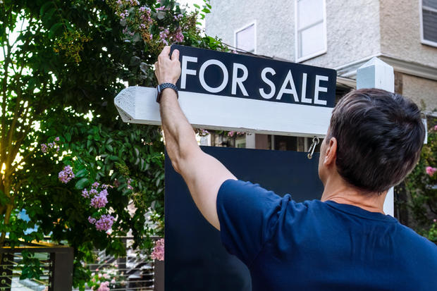 Real estate agent adjusts for sale sign in front yard 
