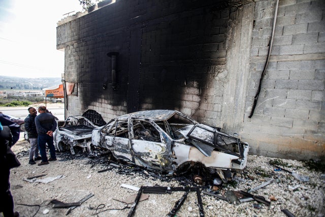 Palestinians inspect damaged building and scorched cars in