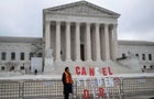 An activist stands next to a sign as they protest in front of the Supreme Court during a rally for student debt cancellation on Feb. 28, 2023. 