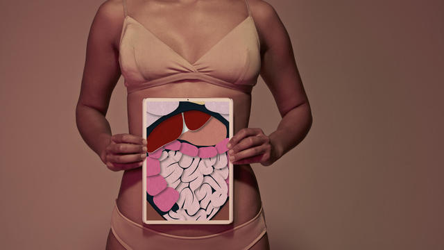 Young woman holding tablet in front of stomach to show intestines 