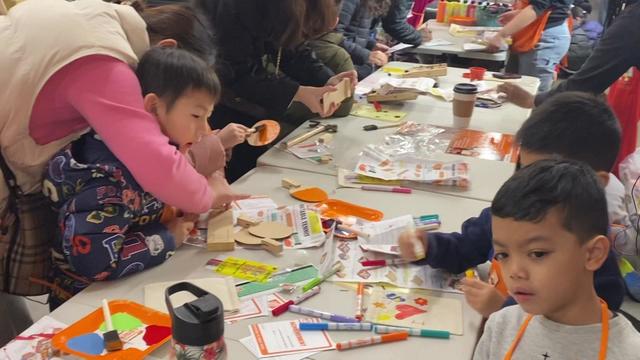 Children and parents do arts-and-crafts activities at a table in a Home Depot. 