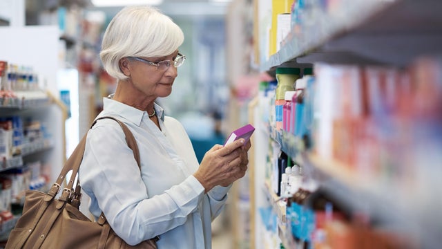 Woman looking at medications on a drug store shelf 