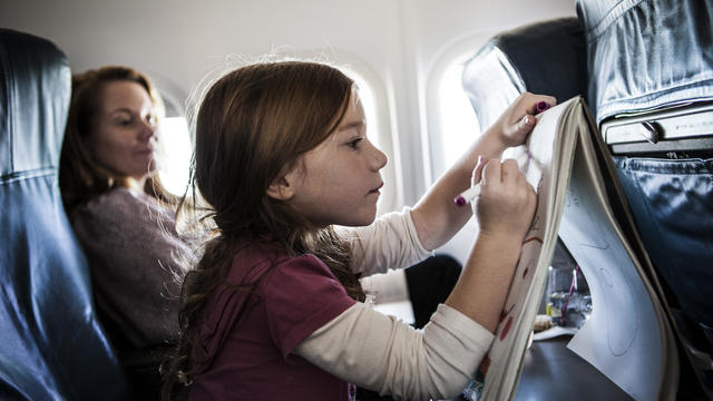 Girl (6yrs) on airplane, drawing on tablet 