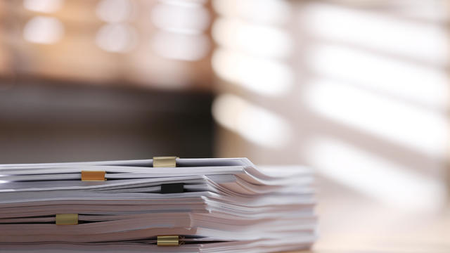 Stack of blank paper with binder clips on wooden table indoors. Space for text 