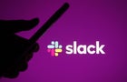 Someone holding a phone against the backdrop of the Slack logo 