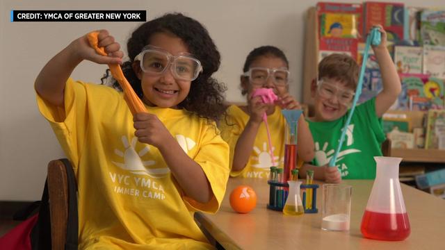 Three children pose with science equipment at YMCA summer camp. 