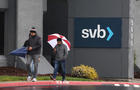 Two people walking in front of sign reading "SVB" 