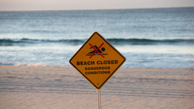 A sign with the statement "Beach closed" and the "no swimming" symbol is showed at Bondi Beach, Sydney, New South Wales, Australia. 
