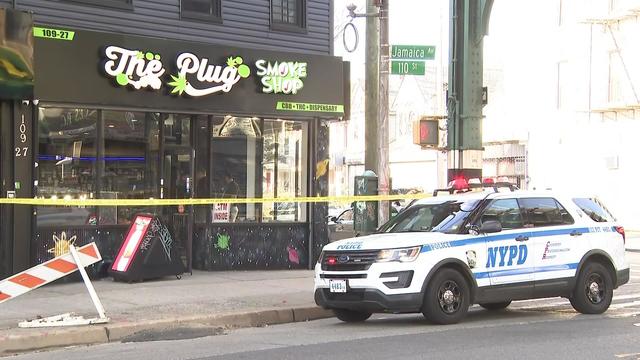 A NYPD vehicle sits parked outside the Plug Smoke Shop, which is blocked off by crime scene tape. 