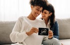 Same-sex pregnant couple holding up their ultrasound scan 