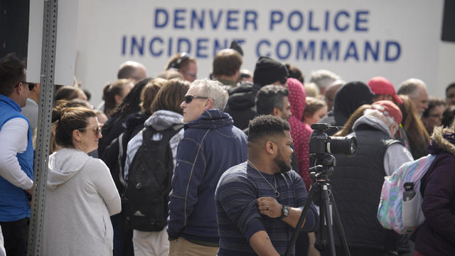 Parents wait for students to be walked out after two administrators were shot and wounded after a handgun was found during a daily search of a student at Denver's East High School March 22, 2023. 