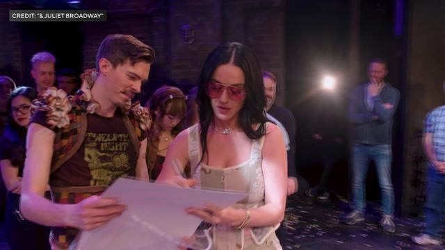 Katy Perry autographs a poster for a "& Juliet" cast member. 