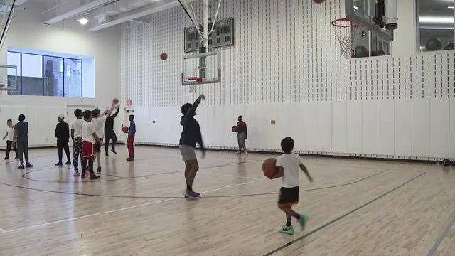 Children play basketball in a gymnasium. 