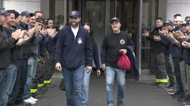 Firefighter James Spoto walks out of a hospital as people applaud. 