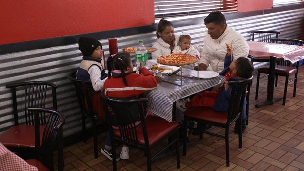 mayorkas-6-migrant-family-enjoying-pizza-in-america.jpg