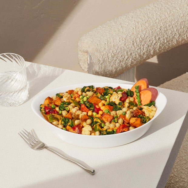 Prepared coconut curry harvest bake sitting in a white bowl on a white table with fork