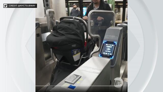 A man pushes a baby stroller through a wide aisle MTA fare gate. 