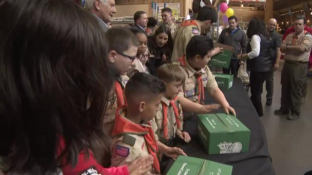 Boy Scouts stand at a table to pack boxes with holiday food. 